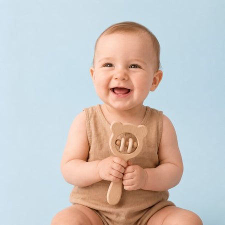 Bébé souriant tenant un hochet de dentition en bois naturel forme ours - Bébé Lova