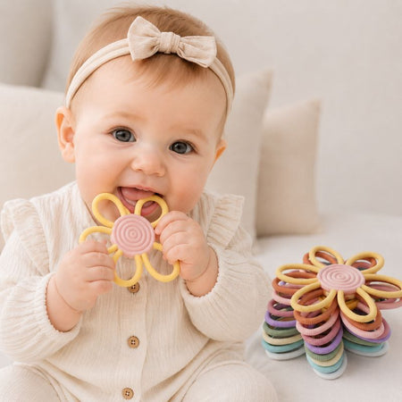 Bébé mordillant un anneau de dentition fleur jaune pastel avec pile d'anneaux colorés - Bébé Lova