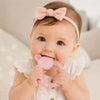 Bébé fille mordillant un anneau de dentition hochet en silicone rose pour soulager les poussées dentaires - Bébé Lova