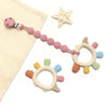 Anneau de dentition dinosaure avec attache tétine en silicone rose sur fond neutre - Bébé Lova