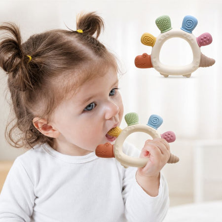 Bébé fille mordillant un anneau de dentition dinosaure sensoriel aux couleurs pastel - Bébé Lova