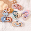 Bracelets de dentition sensoriels en silicone et bois présentés sur couverture en maille pour bébé - Bébé Lova