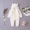 Barboteuse bébé tricot beige à capuche présentée avec chaussons et fleurs - Bébé Lova