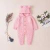 Barboteuse bébé tricot rose à capuche posée à plat avec fleurs séchées et coton - Bébé Lova