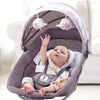Bébé éveillé dans une balancelle évolutive rose avec jouets suspendus - Bébé Lova