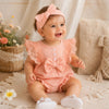 Bébé fille souriante portant un body rose avec dentelle et bandeau assorti dans une ambiance douce - Bébé Lova