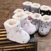 Bottines bébé fourrées à imprimé cœurs et étoiles présentées sur une valise vintage - Bébé Lova
