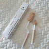 Set de deux brosses de nettoyage en silicone avec boîte présenté sur un dessus-de-lit matelassé rose - Bébé Lova