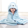 Bébé enveloppé dans une cape de bain BathCape bleue à capuche chien assis sur un tapis - Bébé Lova