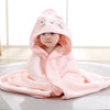 Bébé enveloppé dans une cape de bain BathCape rose à capuche chat assis sur un tapis - Bébé Lova