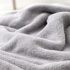 Gros plan sur la texture douce et moelleuse du tissu de la cape de bain BathCape grise - Bébé Lova