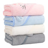 Pile des quatre coloris de capes de bain BathCape : rose, bleu, blanc et gris - Bébé Lova