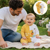 Bébé souriant portant la combinaison à motif ourson dans un jardin aux côtés de son papa - Bébé Lova