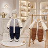Combinaisons bébé d'hiver présentées en boutique sur mannequin et cintre dans une ambiance premium - Bébé Lova