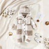 Combinaison bébé à capuche en polaire effet peluche à carreaux beige et blanc, présentée à plat sur une fourrure avec accessoires - Bébé Lova