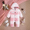 Combinaison bébé à capuche en polaire à carreaux rose et blanc, présentée à plat sur fond rose avec peluche lapin - Bébé Lova