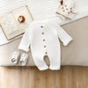 Combinaison tricot bébé blanche mise en scène avec livre et chaussons - Bébé Lova