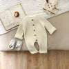 Combinaison tricot bébé coloris écru mise en scène avec livre et chaussons - Bébé Lova