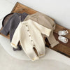 Combinaison tricot bébé présentée en trois coloris gris taupe et écru sur plateau en bois - Bébé Lova