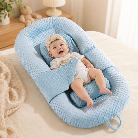 Bébé éveillé souriant dans un coussin anti-reflux incliné bleu avec maintien enveloppant dans une chambre chaleureuse et apaisante - Bébé Lova