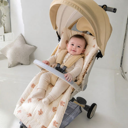 Bébé souriant installé dans une poussette sur un coussin de siège écru à motif lapins BearCush - Bébé Lova