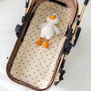 Coussin BearCush écru à petits cœurs marron dans une nacelle de poussette avec une peluche canard - Bébé Lova