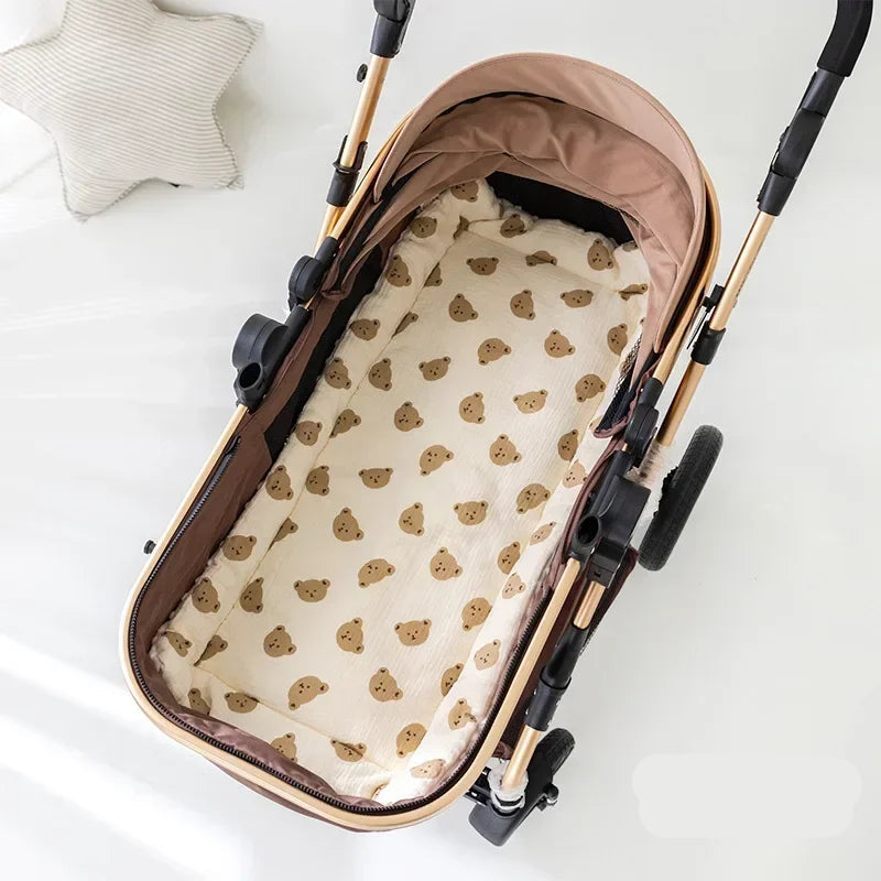Coussin de siège BearCush écru à têtes d'ours vu de dessus dans une nacelle de poussette - Bébé Lova