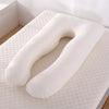 Coussin de grossesse blanc en forme U posé sur un lit avec matelas texturé - Bébé Lova