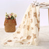 Couverture en mousseline de coton à motif ours drapée sur une table près d'un panier de fleurs - Bébé Lova