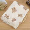 Couverture en mousseline de coton à motif ours pliée sur un panier en rotin - Bébé Lova