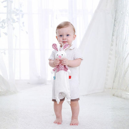 Bébé tenant un doudou plat lapin avec oreilles fleuries et rubans sensoriels - Bébé Lova