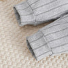 Gros plan sur les bas de pantalon côtelés gris à revers de l'ensemble bébé - Bébé Lova
