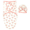 Ensemble couverture d'emmaillotage et bonnet à nœud motif cœur rose sur fond crème présenté à plat - Bébé Lova