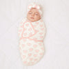 Bébé emmailloté vu de dessus dans la gigoteuse motif cœur rose avec son bonnet turban à nœud - Bébé Lova