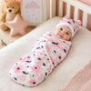 Bébé emmailloté dans un lange fleuri rose avec bonnet assorti dans une chambre cocooning - Bébé Lova
