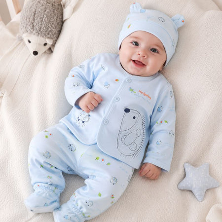 Bébé souriant portant l'ensemble naissance bleu à motif hérisson avec bonnet assorti sur une couverture - Bébé Lova