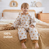Enfant assis sur un lit avec gigoteuse feuilles dorées en coton 100% naturel - Bébé Lova