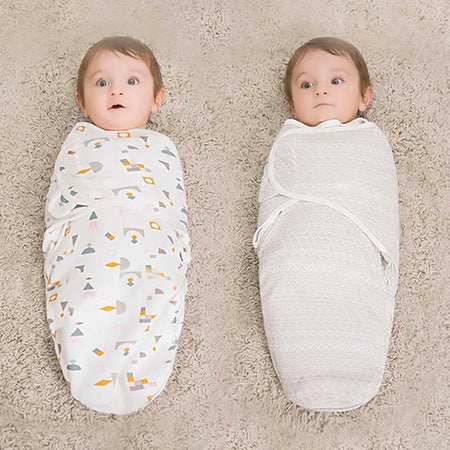 Bébé allongé dans une gigoteuse enveloppante beige en coton sur un lit bébé gris - Bébé Lova