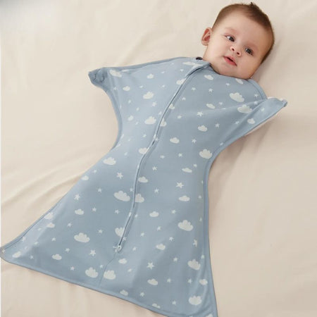 Bébé allongé dans une gigoteuse d’emmaillotage légère bleu ciel à motifs nuages et étoiles - Bébé Lova