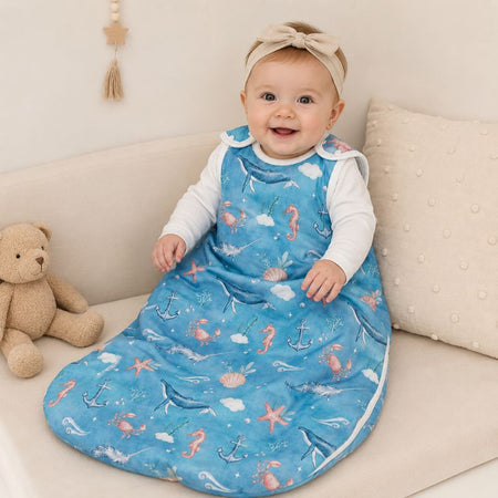 Bébé fille assise sur un canapé dans une gigoteuse évolutive motif océan en situation d’utilisation - Bébé Lova