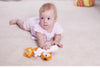 Bébé jouant au sol avec un hochet en peluche doux et coloré - Bébé Lova