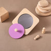 Jouet miroir Montessori en bois avec couvercle rose présenté dans un univers naturel - Bébé Lova