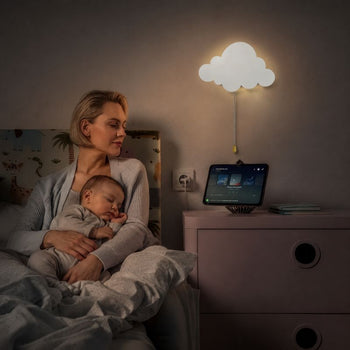 Maman tenant un bébé endormi sous une lampe murale nuage lumineuse dans une chambre bébé apaisante - Bébé Lova