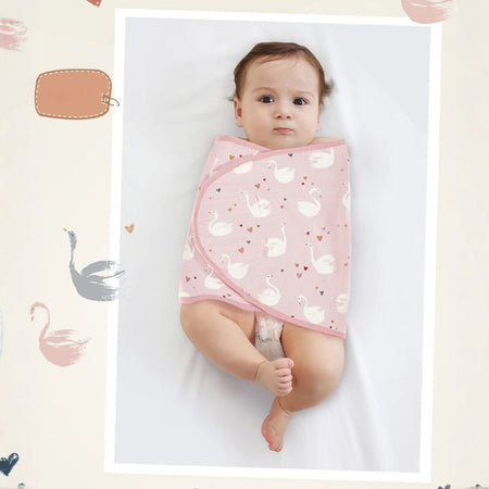 Bébé emmailloté dans un lange à motif cygnes rose, présenté dans un cadre photo décoratif - Bébé Lova