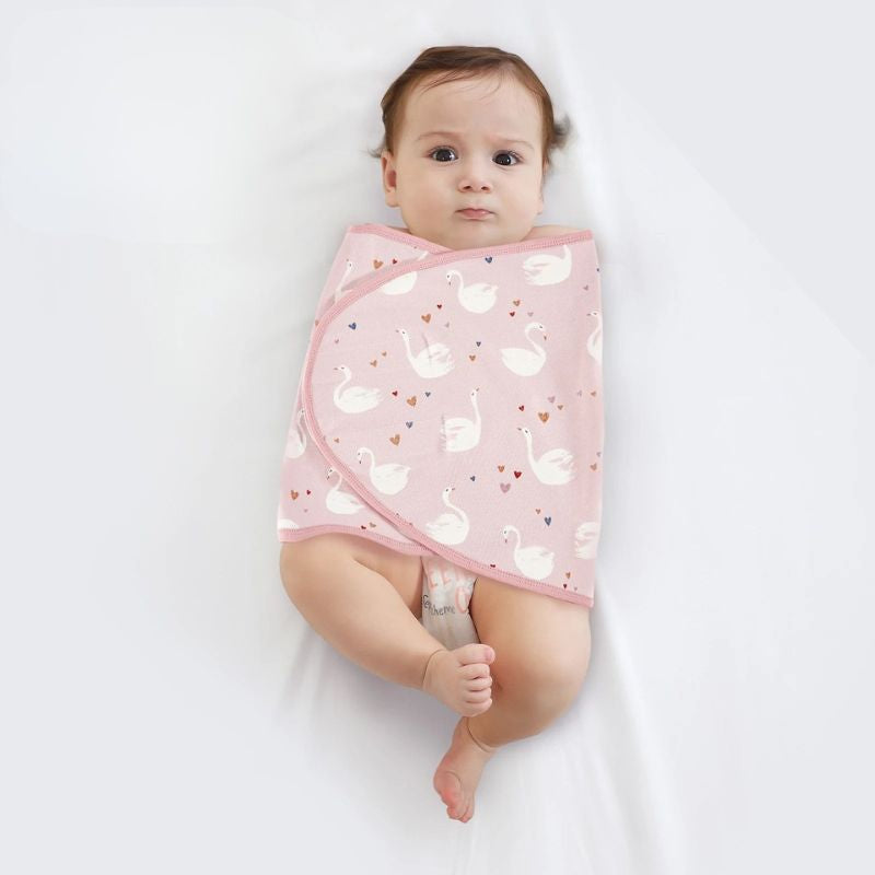 Bébé emmailloté dans un lange à motif cygnes sur fond rose - Bébé Lova