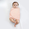 Bébé emmailloté dans un lange à motif pissenlits sur fond rose - Bébé Lova