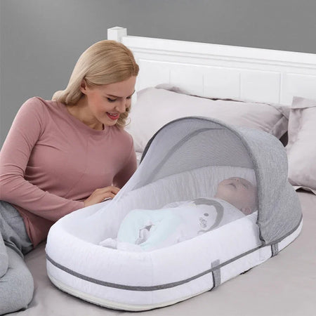 Maman utilisant un berceau pliable avec moustiquaire pour bébé dans une chambre - Bébé Lova