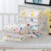 Lot complet de serviettes de bain bébé en coton gaze pliées sur un matelas de lit enfant - Bébé Lova