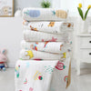 Pile de serviettes de bain bébé en coton gaze aux motifs variés dans une chambre d'enfant - Bébé Lova