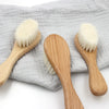 Alt-text : Brosses bébé à poils ultra doux en bois de hêtre sur tissu gris - Bébé Lova